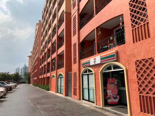 ein rotes Backsteingebäude mit Autos auf einer Straße in der Unterkunft Seven Seas Condo Resort in Jomtien Beach