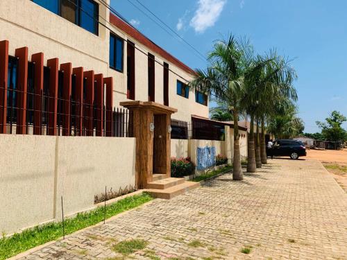 a brick sidewalk next to a building with a palm tree at Résidence Hôtelière Lauria in Lomé