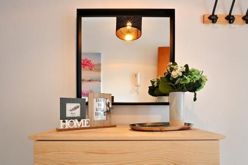 a mirror on top of a dresser with a vase of flowers at Alojamiento Alcantara in Alora