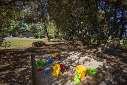 a sandbox with toys in the sand under a tree at Mas Pratsevall in Taradell