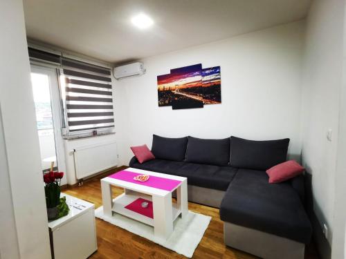 uma sala de estar com um sofá preto e uma mesa em Apartman Lena em Doboj