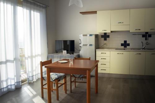 a kitchen with a table and chairs and a refrigerator at Residence La Quiete in Alba