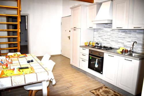 eine Küche mit weißen Schränken, einem Tisch und einem Herd in der Unterkunft Casa Lello in Taranto