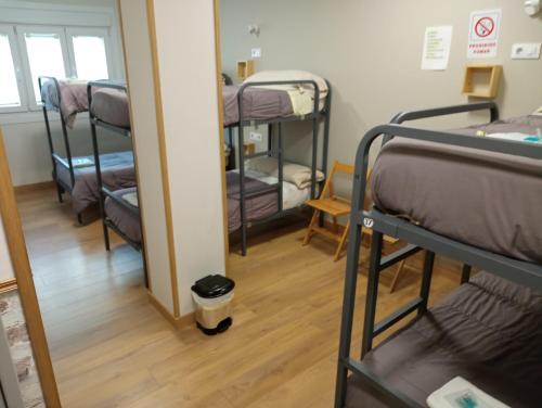 a room with several bunk beds and a mirror at Albergue Camiño Real in Sigüeiro