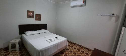 um quarto com uma cama branca num quarto em Astro Hotel em Rondonópolis