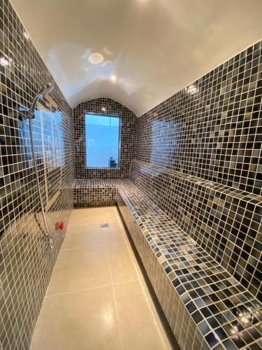 a tiled bathroom with a shower and a window at Pool and Steam room House in the heart of Muscat in Muscat