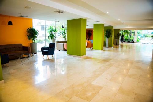 eine Lobby mit grünen Säulen, einem Sofa und Stühlen in der Unterkunft Hotel Barranquilla Plaza in Barranquilla