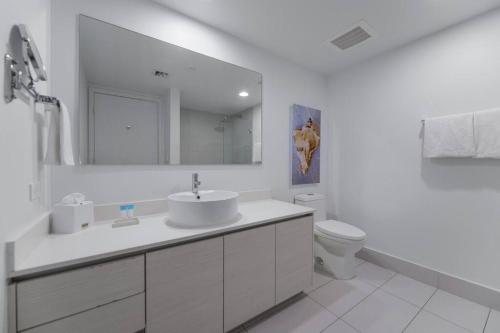 a white bathroom with a sink and a toilet at Cozy 1BR Condo Beachwalk Resort in Hallandale Beach