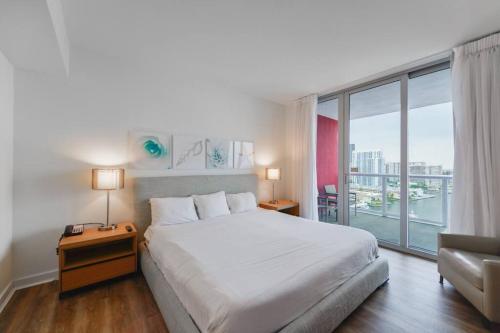 a bedroom with a white bed and a large window at Cozy 1BR Condo Beachwalk Resort in Hallandale Beach