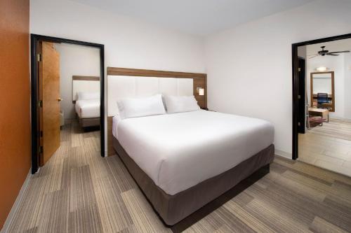 Holiday Inn Express & Suites San Antonio - Downtown Market Area, an IHG Hotel في سان انطونيو: غرفة نوم بسرير ابيض كبير ومرآة