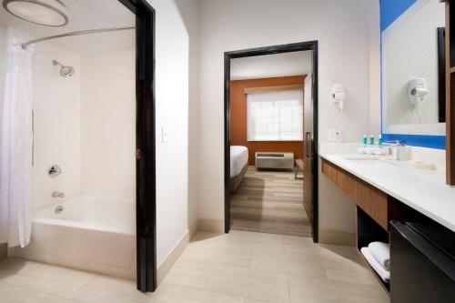 ein Badezimmer mit einer Badewanne, einem Waschbecken und einem Spiegel in der Unterkunft Holiday Inn Express & Suites San Antonio - Downtown Market Area, an IHG Hotel in San Antonio