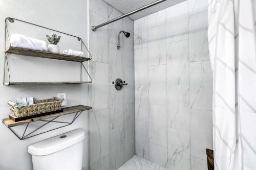 a white bathroom with a shower and a toilet at Merritt Island Oasis with Pool about 7 Mi to Beach! in Merritt Island