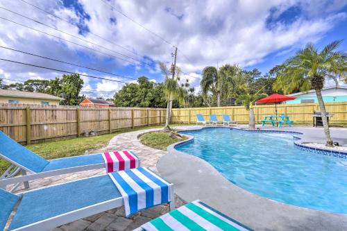 a swimming pool with blue and white chairs and a fence at Merritt Island Oasis with Pool about 7 Mi to Beach! in Merritt Island