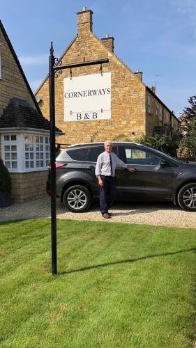 a man is standing next to a car at Cornerways B&B in Chipping Campden