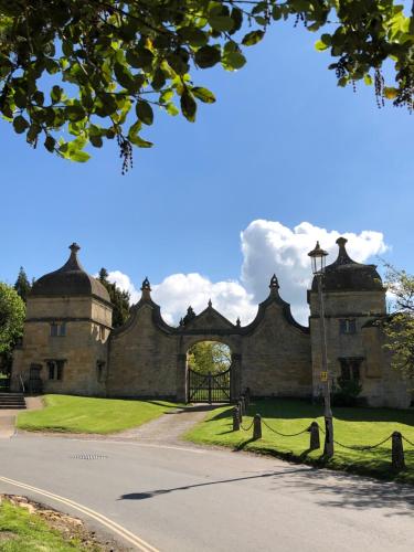 an old stone building with a gate in the grass at Cornerways B&B in Chipping Campden