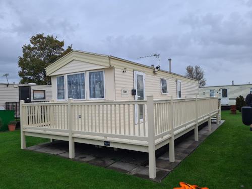a white house with a porch and a deck at 6 berth 3 bedroom Northshore Skegness FREE WIFI in Skegness