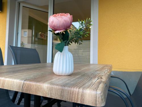 a pink rose in a white vase on a table at Hempis Ferienwohnungen in Hochkirch