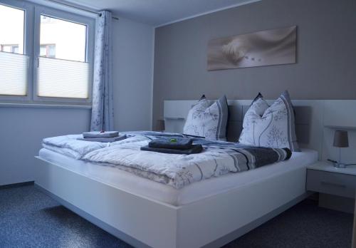 a white bedroom with a large white bed with pillows at Hempis Ferienwohnungen in Hochkirch