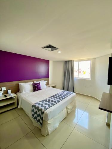 a bedroom with a large bed with a purple wall at Nobile Suítes Tambaú in João Pessoa