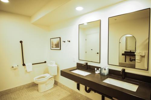 a bathroom with two sinks and a toilet and a mirror at Baymont by Wyndham Fort McMurray in Fort McMurray