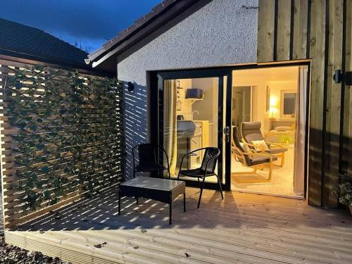 a wooden deck with a chair and a table at Little Slioch Cottage- A Break From City Life in Avoch