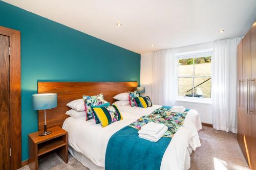 - une chambre avec 2 lits et un mur bleu dans l'établissement The Shore Apartment, à Queensferry