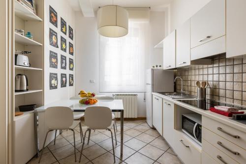kuchnia z białymi szafkami, stołem i krzesłami w obiekcie Portobello Apartments w Bolonii