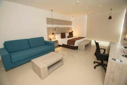 a hotel room with a bed and a blue couch at Hotel Barranquilla Plaza in Barranquilla