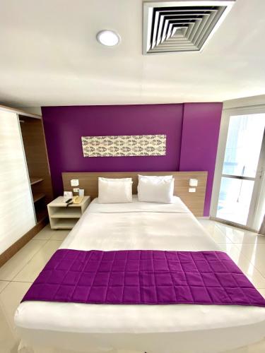 a purple bedroom with a large bed with a purple headboard at Nobile Suítes Tambaú in João Pessoa