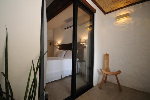 Habitación con espejo, silla y cama en Villa Santa Fé, en Búzios