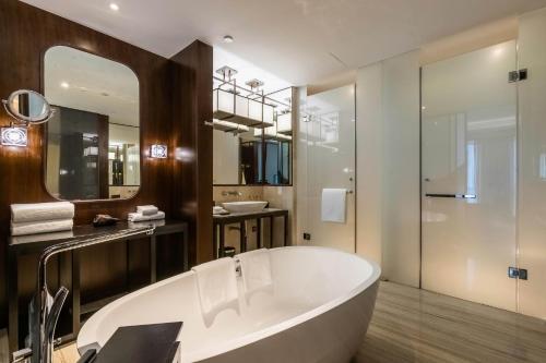 a bathroom with a large tub and a mirror at HUALUXE Wuxi Taihu, an IHG Hotel in Wuxi