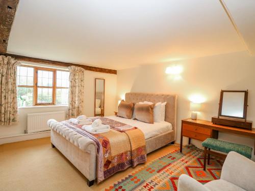 a bedroom with a bed and a desk and a mirror at Manor Farm House in Norwich