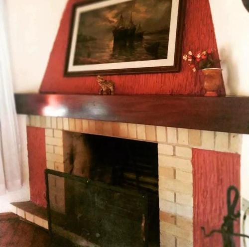 a fireplace with a painting on top of it at Pequeno Paraiso in Campos do Jordão