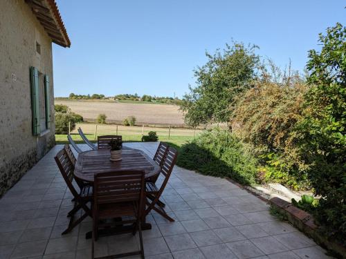 a wooden table and chairs on a patio at Gîte de charme avec jardin, proche d'Aubeterre-sur-Dronne, pour 6 pers., cheminée, WIFI, équipements bébé - FR-1-653-116 in Bellon