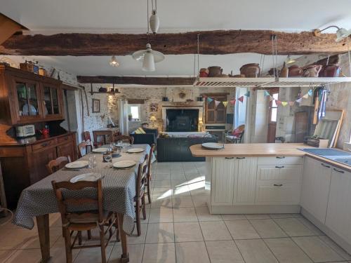 a kitchen and dining room with a table and chairs at Maison familiale avec grand jardin près du Périgord - 3 chambres, WIFI et vélos fournis - FR-1-653-171 in Combiers
