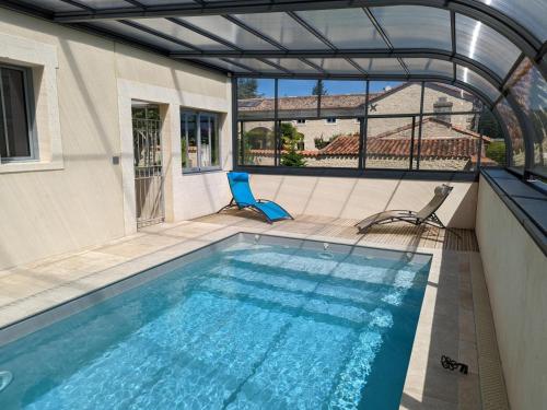 une piscine avec deux chaises à côté d'une maison dans l'établissement Gîte rénové avec piscine chauffée, sauna, fitness et jardin à Salles-de-Barbezieux - FR-1-653-218, à Salles-de-Barbezieux