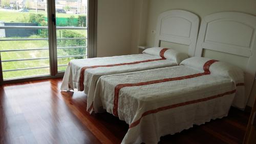 two beds in a room with a large window at Chalet en Somió con finca independiente in Gijón