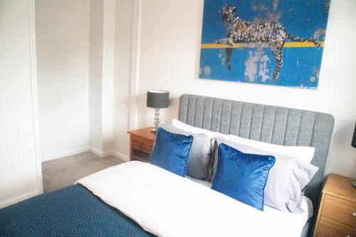 a bedroom with a bed with blue and white pillows at Lovely 1 bedroom Apartment in Central High Wycombe in Buckinghamshire