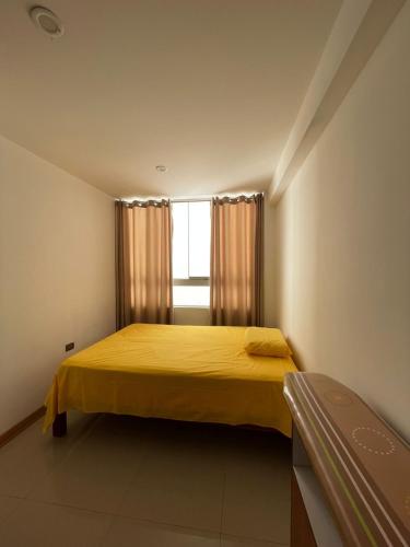 Un dormitorio con una cama amarilla y una ventana en Hermosa departamento vanguardista c/ balcon ., en Trujillo