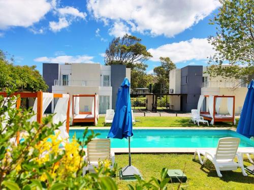 a pool with chairs and umbrellas in the yard at Las Martinas Piriapolis in Piriápolis