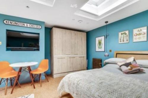 sypialnia z niebieskimi ścianami, łóżkiem i stołem w obiekcie Stylish Notting Hill Air Conditioned studio w Londynie