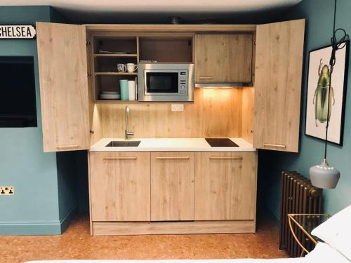 a kitchen with wooden cabinets and a microwave at Stylish Notting Hill Air Conditioned studio in London