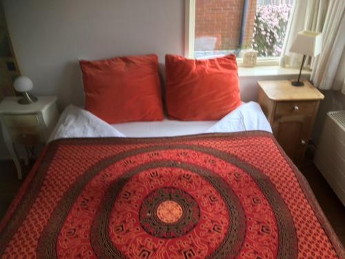 un letto con cuscini rossi e una coperta rossa sopra di B&B Canal Sight ad Amsterdam