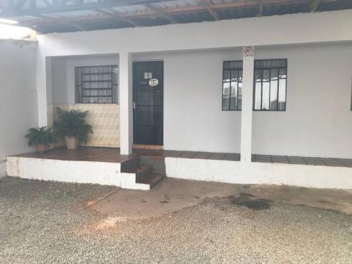 een wit gebouw met een zwarte deur en een plant bij Casa com 2 quartos agradáveis com ar condicionado in Foz do Iguaçu