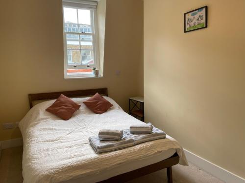 a bedroom with a bed with two towels on it at Penguin Flat in London