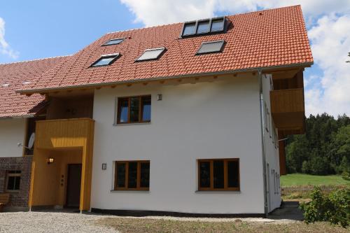 une maison blanche avec un toit rouge dans l'établissement BachLauf im Happy Allgäu, à Leutkirch im Allgäu