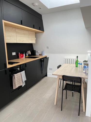 a kitchen with a wooden table and black cabinets at Penguin Flat in London