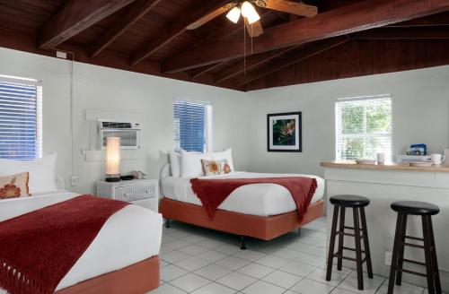 基韋斯特的住宿－南風汽車旅館，一间卧室设有两张床和两张凳子。