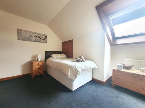 a bedroom with a bed and a dresser and a window at Taigh Mairi Grimsay in Carinish