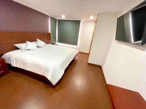 1 dormitorio con 1 cama con sábanas y almohadas blancas en HOTEL HOME, en Pasto